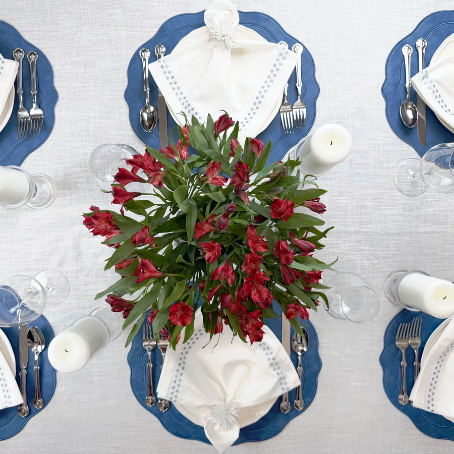 Overhead view of a full table set with Blue placemats and red alstroemeria