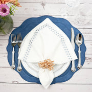 Blue placemat with a white gray-dot embroidered napkin and wood bead napkin ring on whitewashed wood
