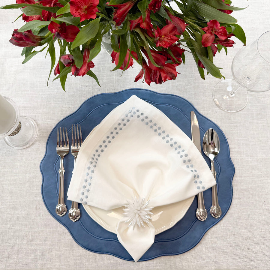 Blue placemat with a white dot napkin, white flower napkin ring and red alstroemeria