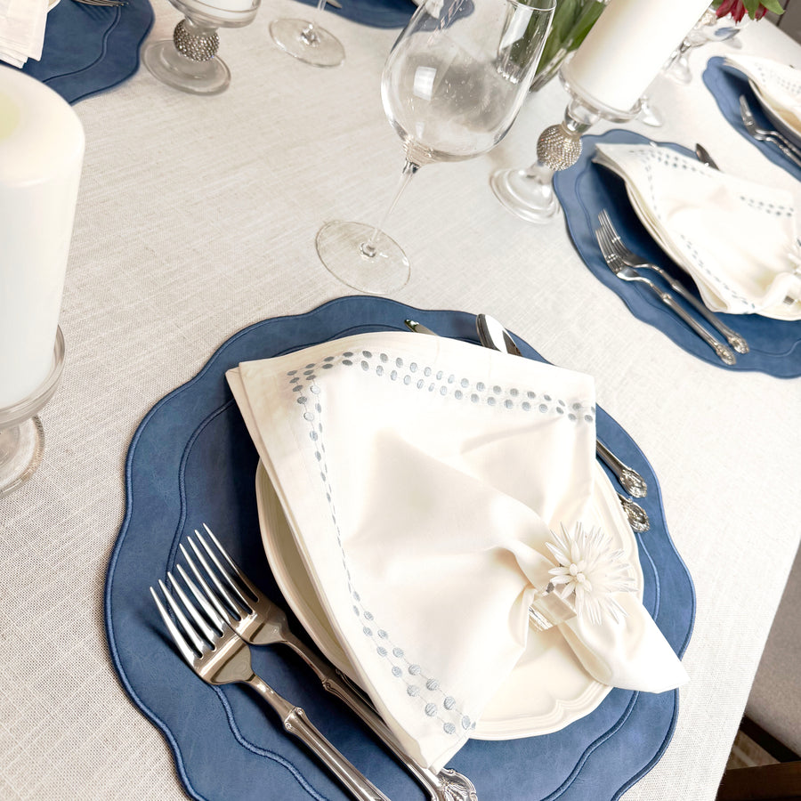Angled view of a table set with Blue scalloped placemats and candles