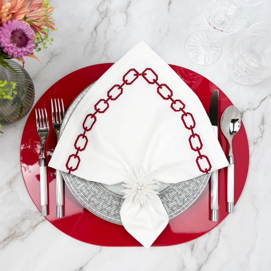 Red Kelly lacquered wood placemat with a red-and-white embroidered napkin and silver flatware