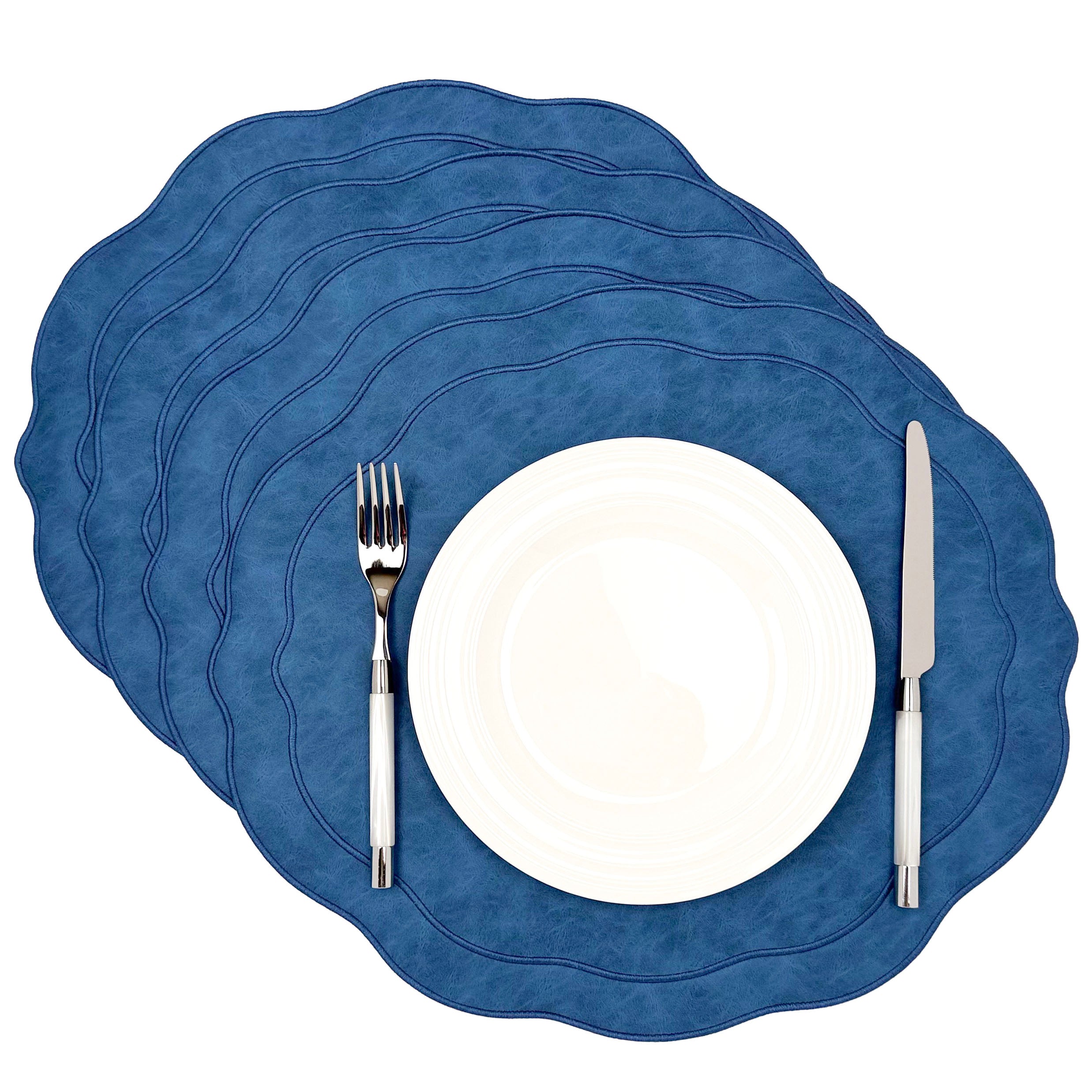 Set of 4 Blue scalloped faux leather placemats stacked with a white plate, fork and knife