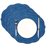 Set of 4 Blue scalloped faux leather placemats stacked with a white plate, fork and knife