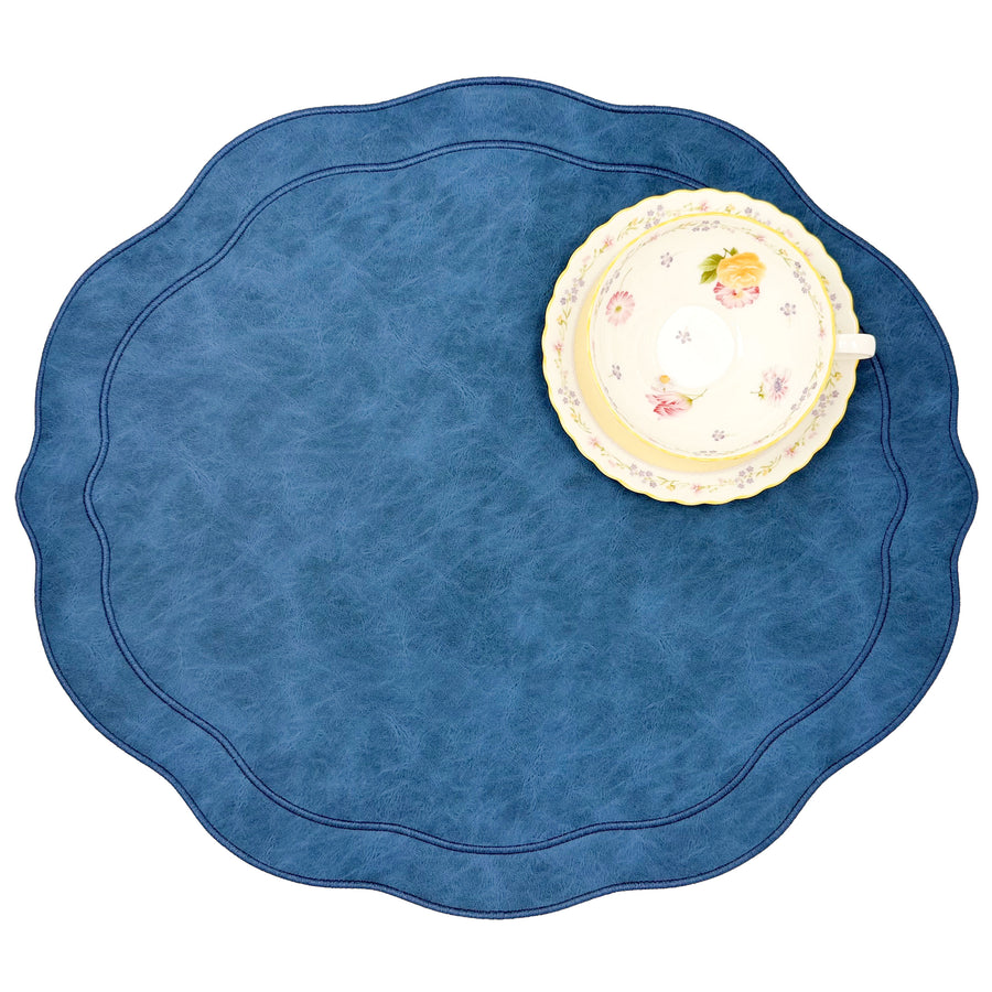 Blue scalloped faux leather placemat with a floral teacup and saucer